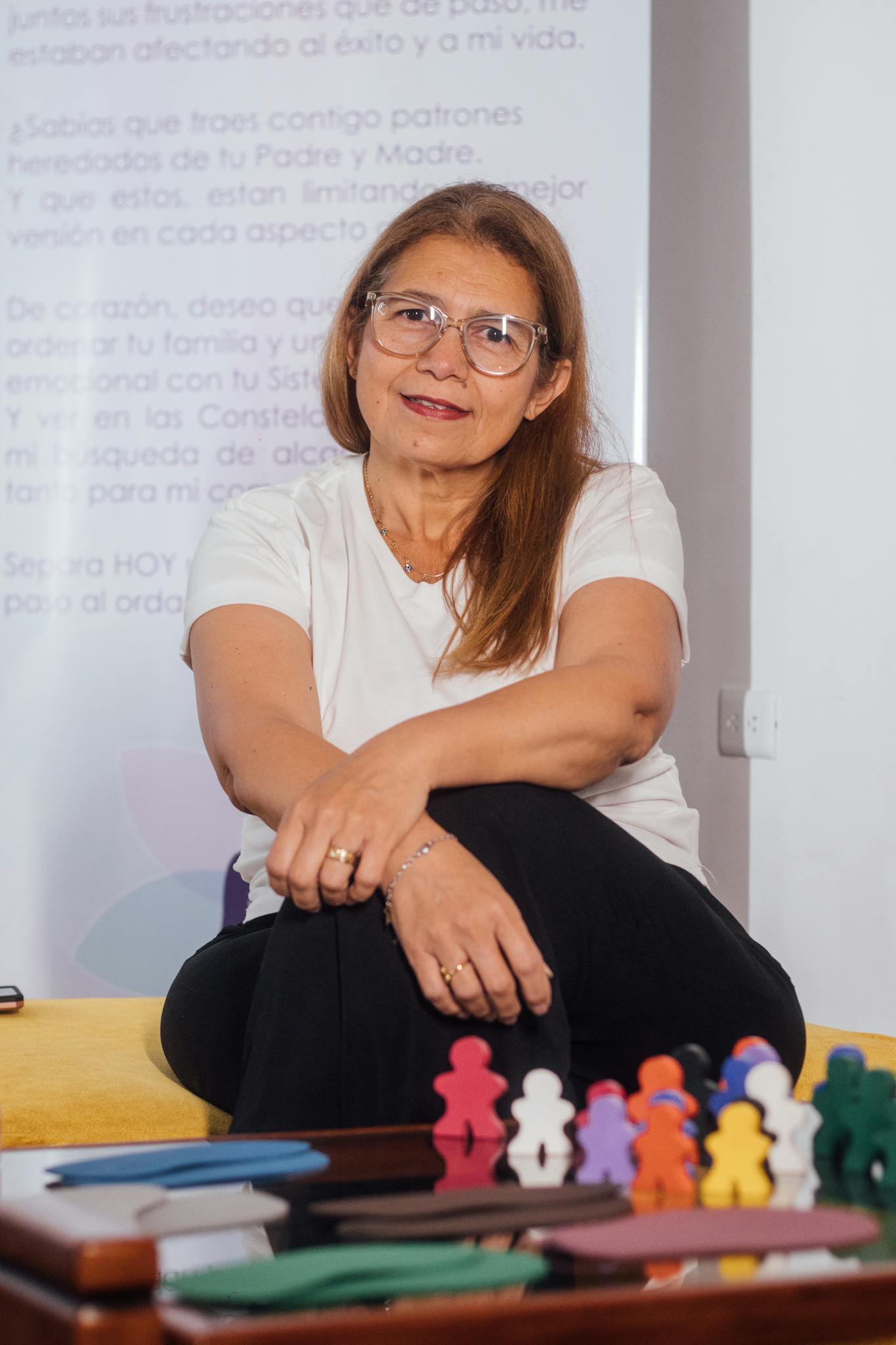 Middle-aged woman sitting with colorful family therapy tools on a table indoors.